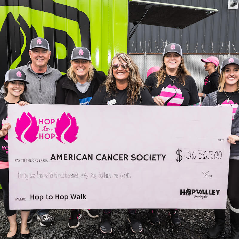 people holding a check from hop to hop to the american cancer society