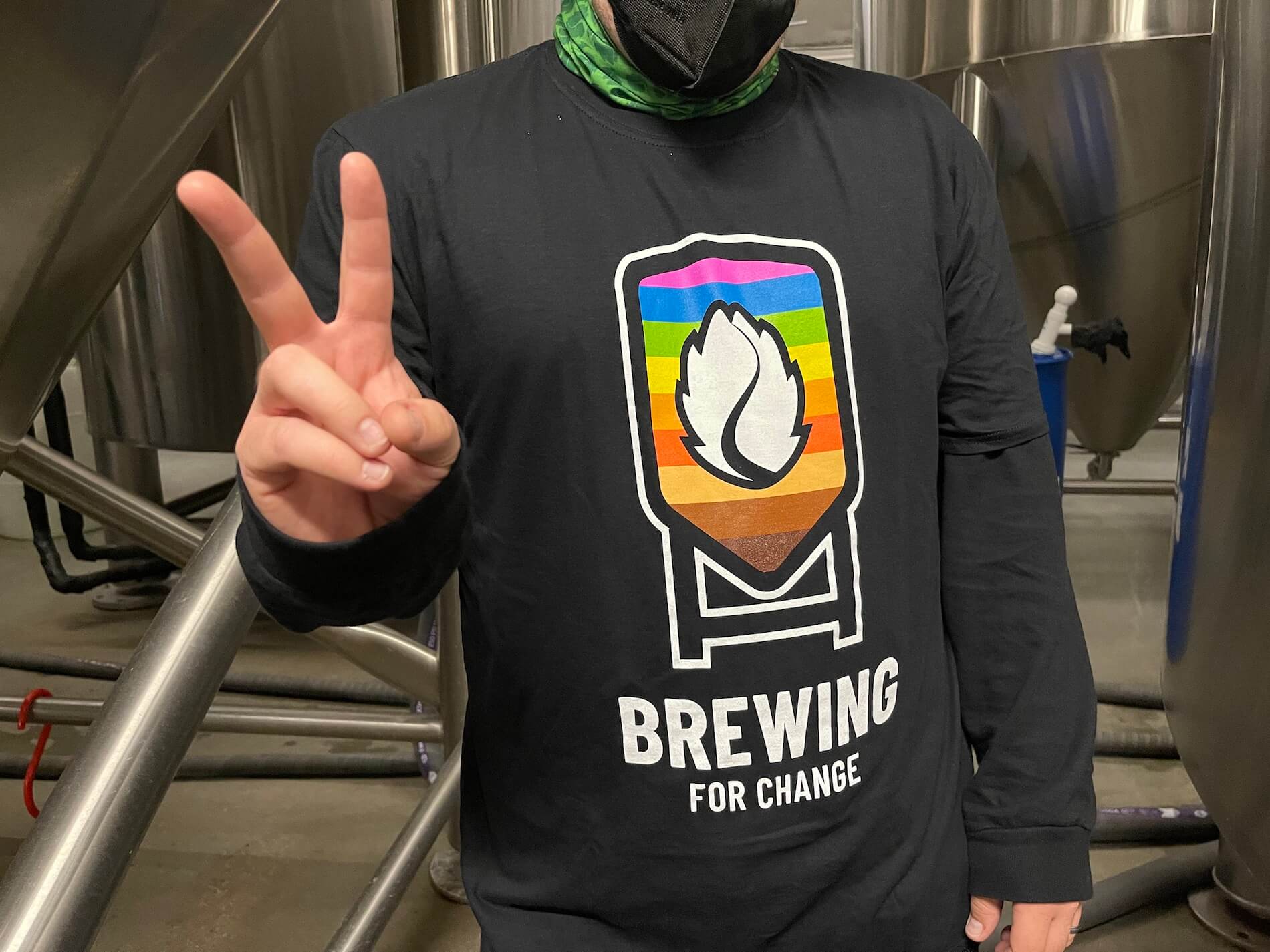 man doing the peace sign, wearing brewing for change shirt 