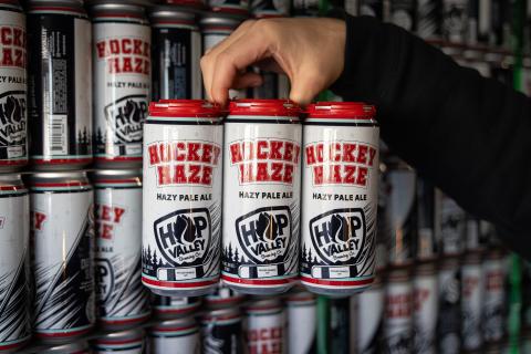 Hand holding 6pk of Hockey Haze in red toppers